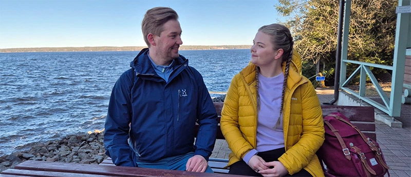 Kuvituskuva: kaksi henkilöä järven rannalla.