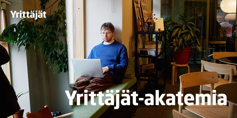Yrittäjät-akatemian banneri, jossa mies istuu läppärin kanssa kahvilassa ikkunalaudalla