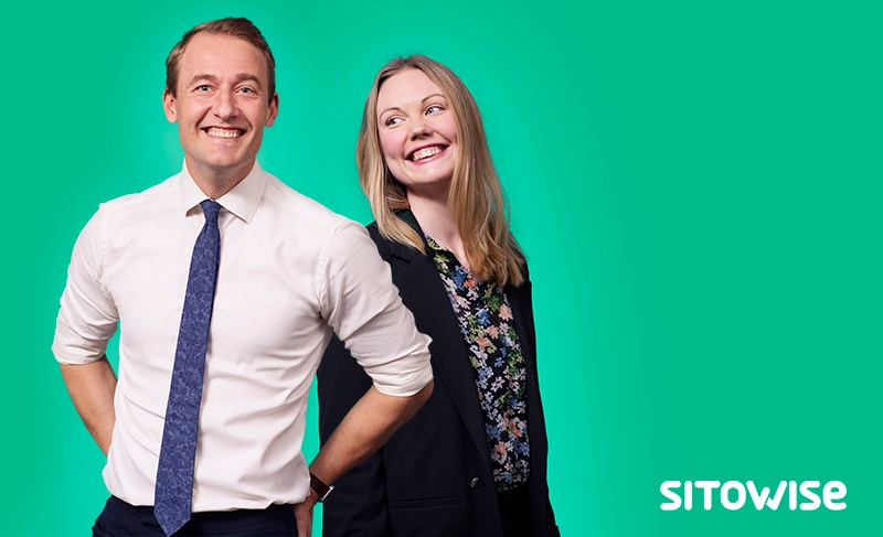 Kaksi iloista henkilöä, joista toinen katsoo kameraan.